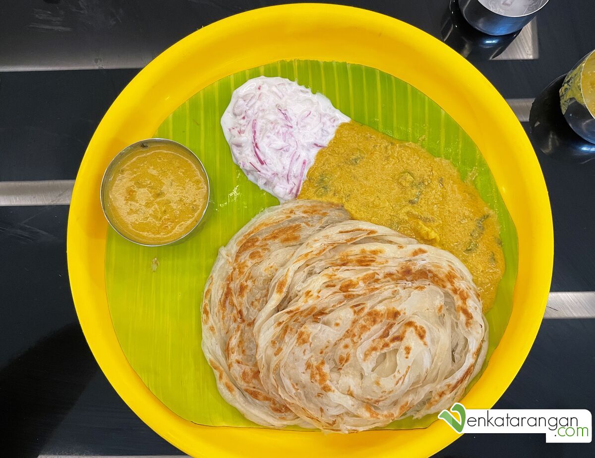 Parotta (layered version of Indian flatbread made with refined wheat) with vegetarian kurma (spicy gravy) and onion raita (yogurt dip)