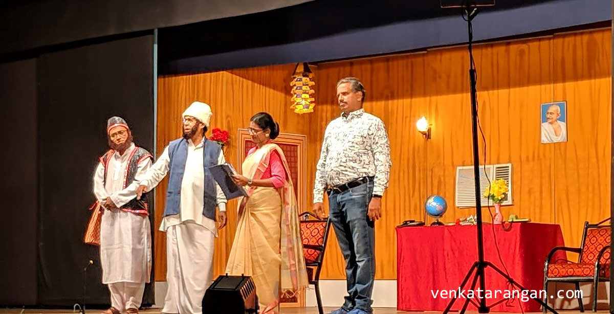 T.V. Varadharajen, acting as Muhammad bin Tughluq who has become the Chief Minister of Tamil Nadu. Next to him is the actress appearing as the chief secretary of Tamil Nadu Government.