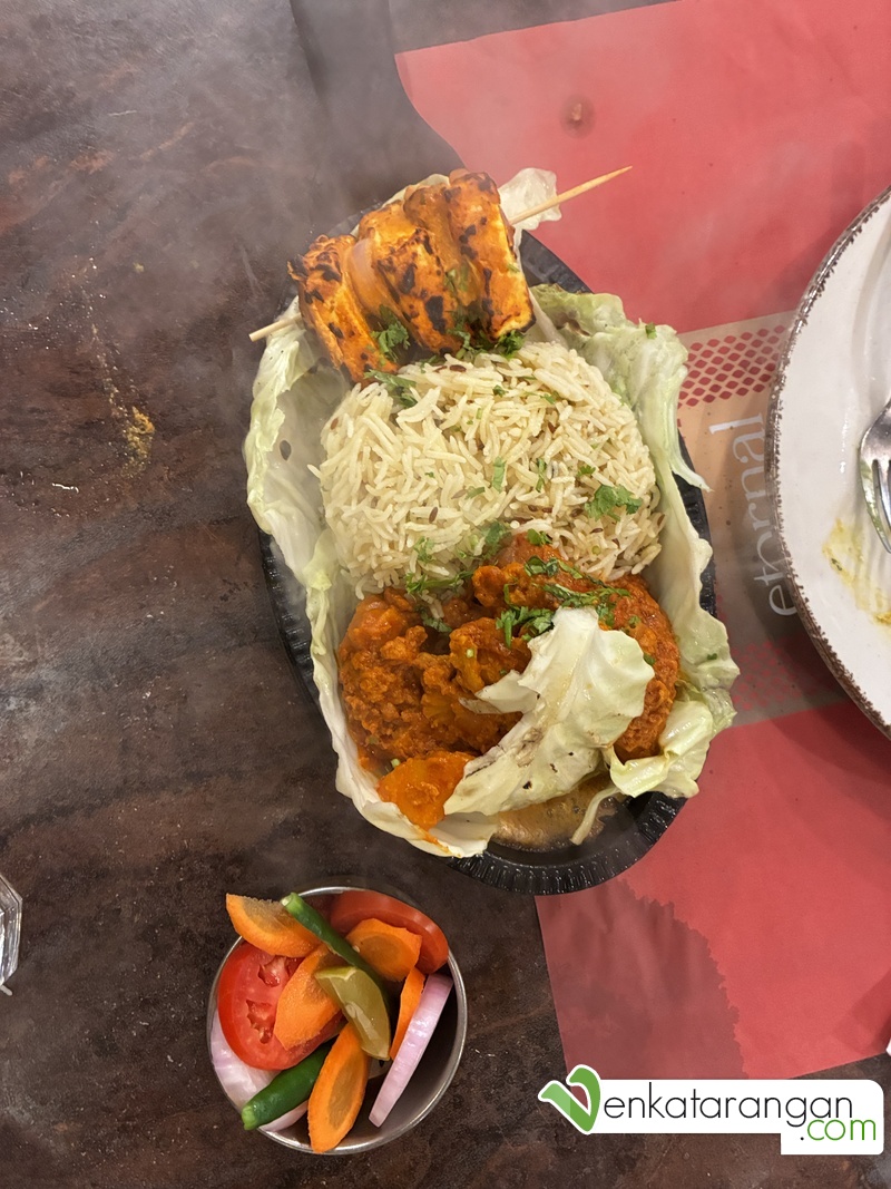 Indian Sizzler - Aloo Gobi Masala, Jeera Pulao, Achari Paneer Tikka, Geen Salad in a sizzler plate